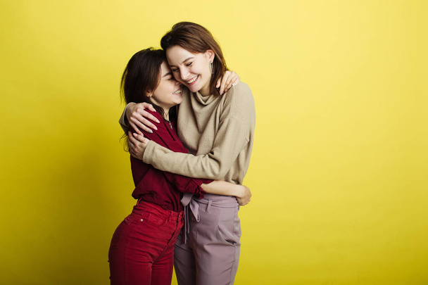 Image of happy young girls standing isolated over yellow background. Girls - Foto, afbeelding