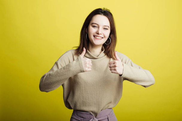 Image of happy young girl standing isolated over yellow background. Girl - Photo, Image