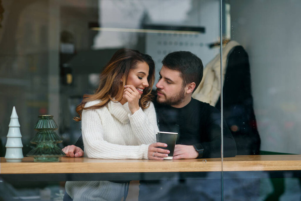 Dating in a cafe. Beautiful smiling girl with her boyfriend sitting in a cafe enjoying in coffee and conversation. - Foto, immagini