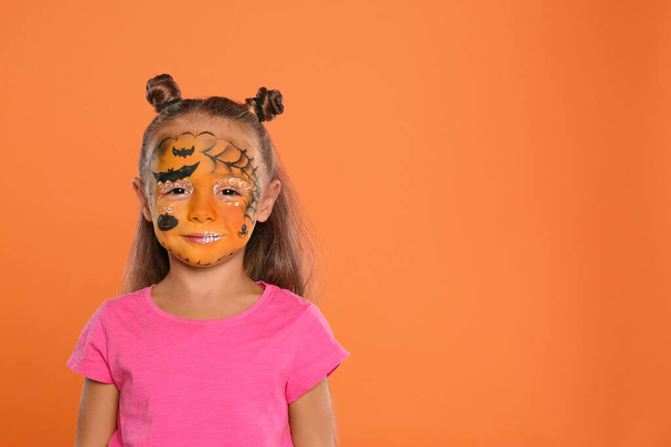 Χαριτωμένο κοριτσάκι με προσωπογραφία σε πορτοκαλί φόντο. Χώρος για κείμενο - Φωτογραφία, εικόνα