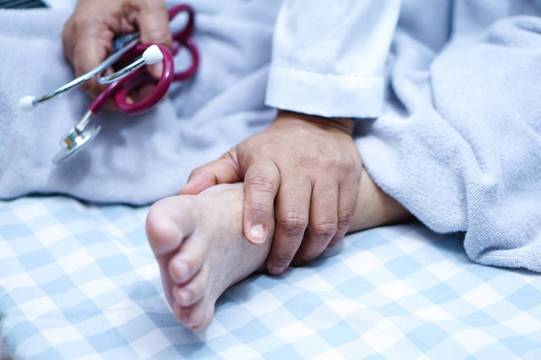 Arzt berührt Fuß einer asiatischen Seniorin oder älteren Patientin mit Liebe, Fürsorge, Hilfe, Ermutigung und Empathie auf der Krankenstation: gesundes starkes medizinisches Konzept - Foto, Bild