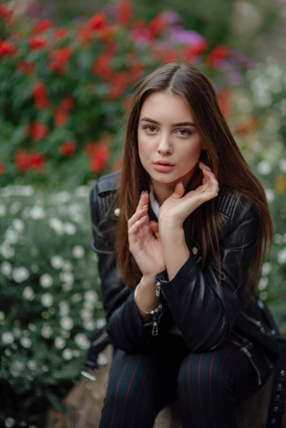 young girl in a black leather jacket stands on the background of a city street.Girl in a leather jacket - Фото, зображення
