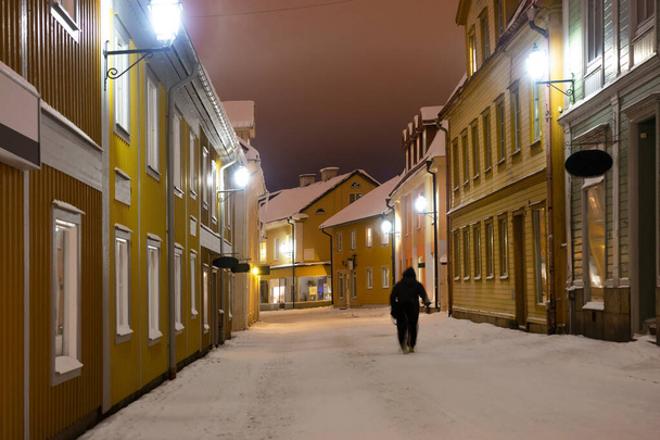 Pessoa em movimento desfocado andando na pequena rua da cidade velha na noite de inverno
 - Foto, Imagem