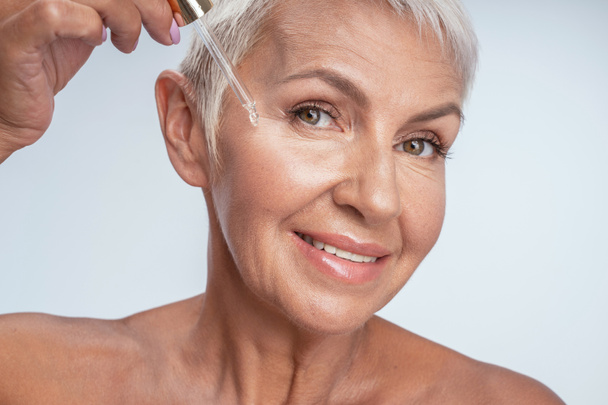 Positive delighted senior woman doing beauty procedures - Фото, изображение