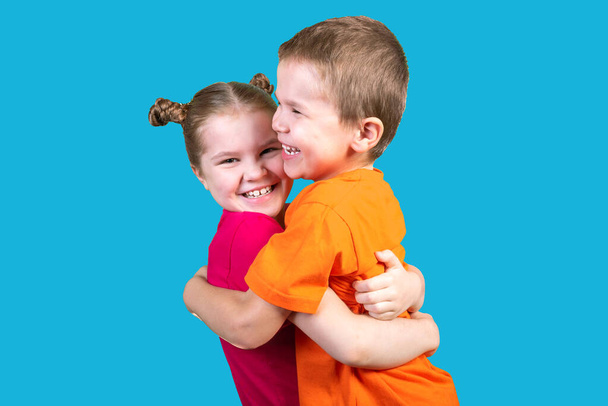 Брат и сестра обнимаются в изоляции, на синем фоне
. - Фото, изображение