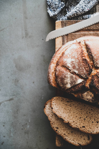 Tasainen-lay tuoretta hapantaikina leipää ja leipää viipaleita puulevyllä harmaalla betonipöydällä tausta, ylhäältä näkymä, kopioi tilaa, pystysuora koostumus
 - Valokuva, kuva