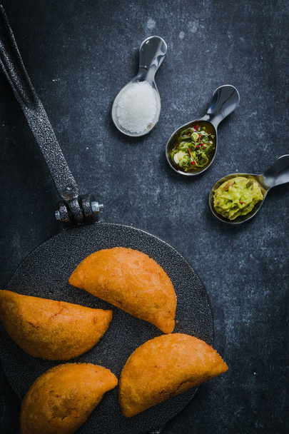 Empanadas (turnovers) on a tortilla presser with aji (hot sauce), salt and guacamole on the side - Photo, Image