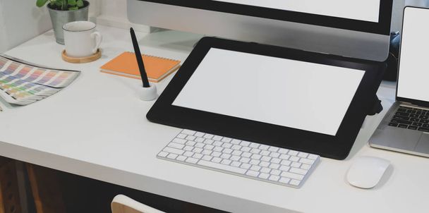 Vista de primer plano del lugar de trabajo de diseño con tableta digital de pantalla en blanco con computadora de escritorio con suministros de oficina
  - Foto, Imagen