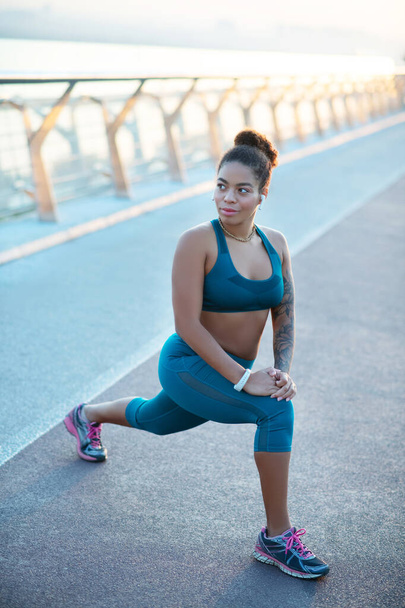 Dark-skinned woman wearing leggings and top stretching after run - Foto, Imagem