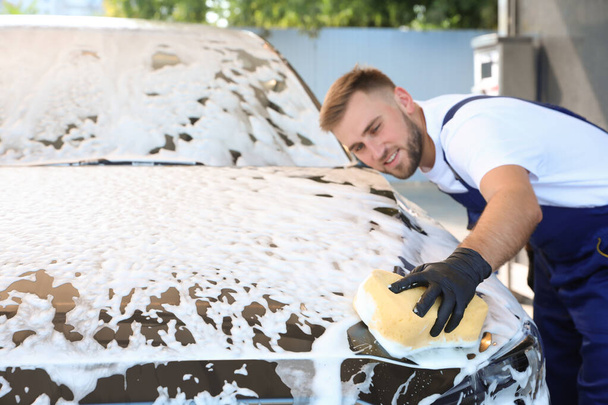Young worker cleaning automobile with sponge at car wash - Foto, Imagem