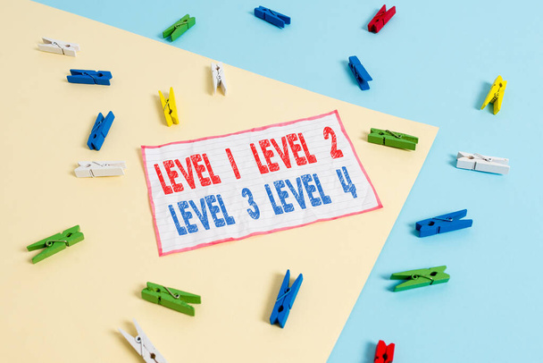 Conceptual hand writing showing Level 1, 2, 3 and 4. Business photo text Steps levels of a process work flow Colored clothespin paper reminder with yellow blue background. - Photo, Image