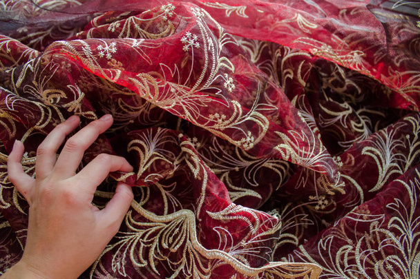 Dívčina ruka s gestem v pořádku na pozadí krajkové červené tylové tkaniny. Tulle textura tkaniny. - Fotografie, Obrázek