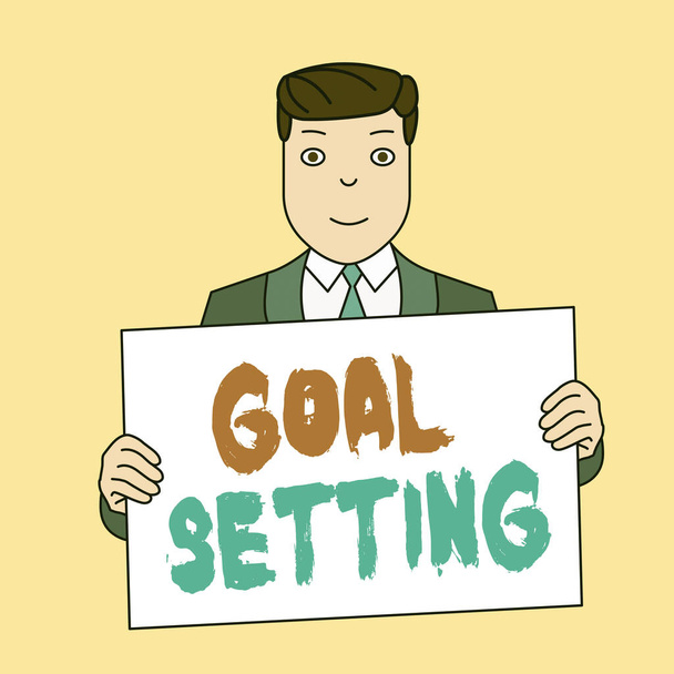 Writing note showing Goal Setting. Business photo showcasing process of identifying something that you want to accomplish Smiling Man Holding Suit Poster Board in Front of Himself. - Photo, Image