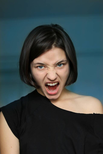 портрет девушки в черной футболке с эмоциями гнева и ненависти
 - Фото, изображение
