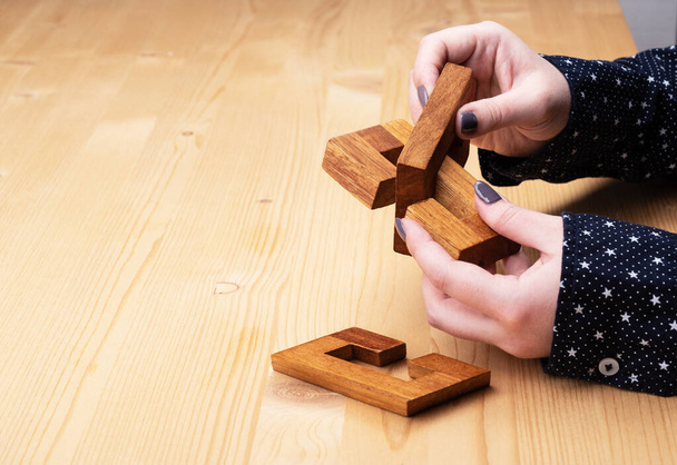 Girl is trying to solve the constructor puzzle oblique knot. - Foto, Bild