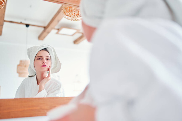 Image of beautiful woman in bathrobe and with towel on her head reflected in mirror - Valokuva, kuva