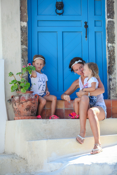 Joven madre y su hija sentadas en la puerta de la vieja casa en Emporio pueblo, Santorini, Grecia
 - Foto, imagen