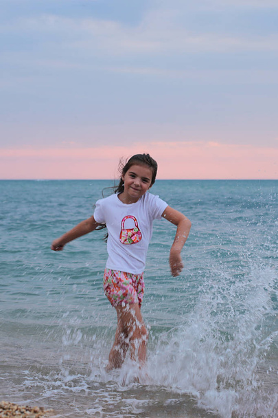 Jovem menina safada de sete anos com cabelos longos se diverte junto ao mar
 - Foto, Imagem