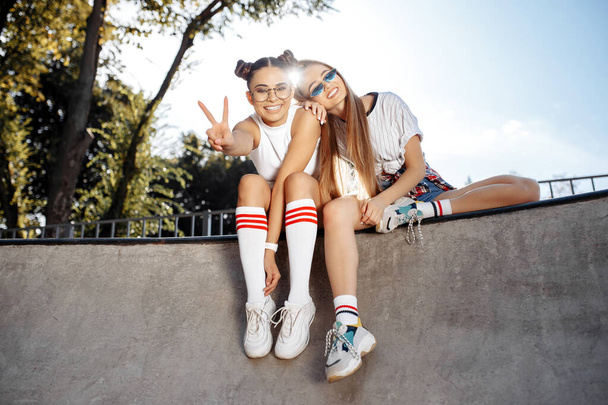 Two carefree young teenage hipster girls posing with happy faces at the skatepark. Freedom and Best Friends concept. - Фото, изображение