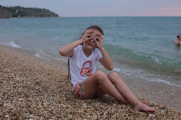 Νεαρό άτακτο κορίτσι επτά ετών με μακριά μαλλιά διασκεδάζει δίπλα στη θάλασσα - Φωτογραφία, εικόνα
