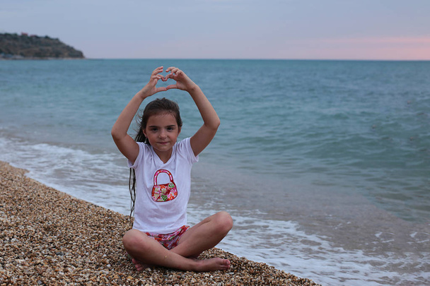 Nuori tuhma tyttö seitsemän vuotta pitkät hiukset on hauskaa meren rannalla
 - Valokuva, kuva