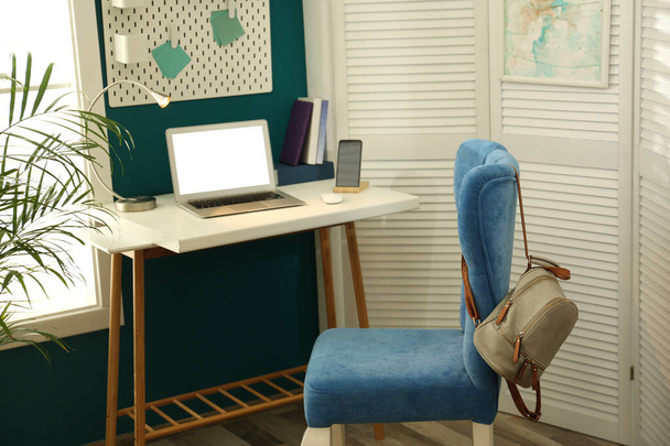 Стильное домашнее рабочее место с элегантным синим стулом возле окна. Дизайн интерьера
 - Фото, изображение
