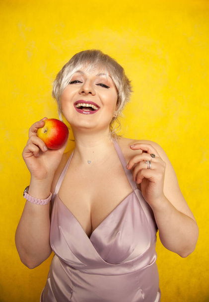 Close up pretty young woman holding an apple shes about to eat - 写真・画像