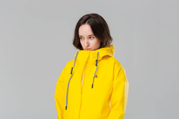 Sad brunette girl in a yellow raincoat. Get ready for bad weather. - Foto, immagini