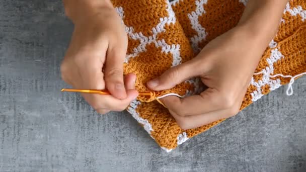 young womans hands crocheting with orange and white cotton thread on stone table background, top view close-up full HD stock video footage in real-time - Footage, Video