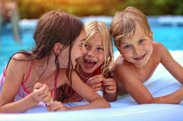 Τα παιδιά διασκεδάζουν στην πισίνα μια ζεστή μέρα. - Φωτογραφία, εικόνα