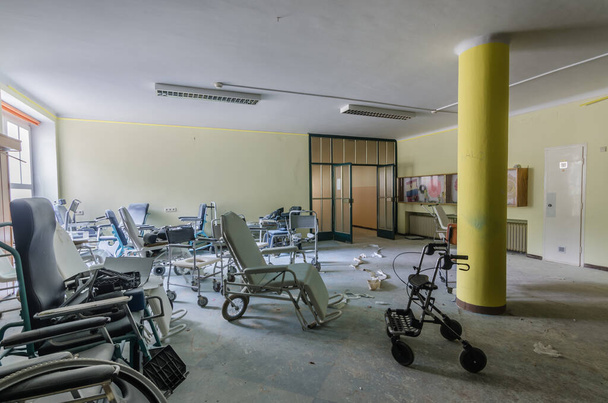 Много разных инвалидных колясок в заброшенной больнице
 - Фото, изображение