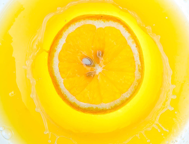 a piece of orange will fall into juice and spray, top view - Foto, Imagem