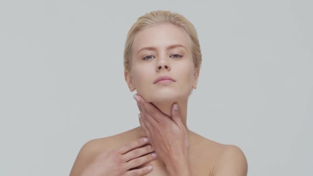 Studio portrait of young, beautiful and natural blond woman applying skin care cream. Face lifting, cosmetics and make-up. - Кадри, відео