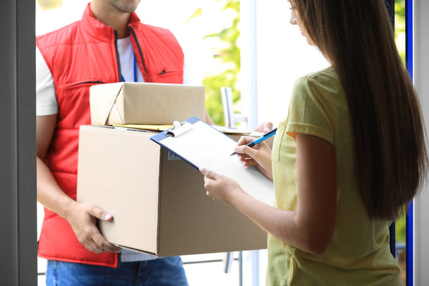 Woman signing for delivered parcels on doorstep, closeup. Courier service - Φωτογραφία, εικόνα