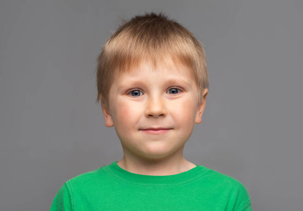 Portrait of happy smiling boy in green t-shirt. Attractive kid in studio. Childhood concept. - Photo, image