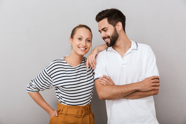 Smiling happy young loving couple friends man and woman posing indoors isolated over grey background. - Foto, afbeelding