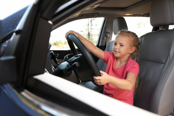 Κοριτσάκι που παίζει με το τιμόνι στο αυτοκίνητο. Οικογενειακό ταξίδι - Φωτογραφία, εικόνα