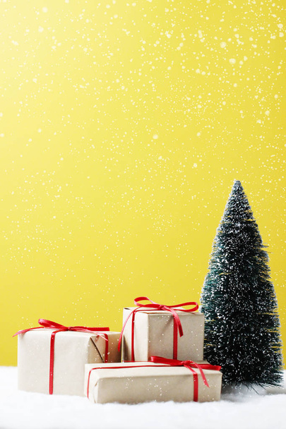 Gift boxes, Christmas tree on table and yellow background. - Photo, Image