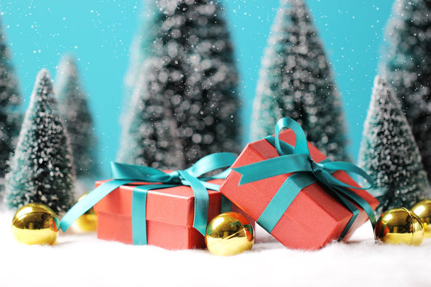Weihnachten Hintergrund mit roten Geschenkboxen, goldenen Kugeln und verschwommenen Weihnachtsbäumen auf dem Tisch. - Foto, Bild