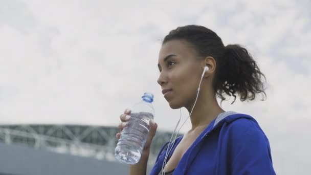 Afro-amerikai futó nő vizet iszik futás után. Portré Fitness nő ivóvíz palack. - Felvétel, videó