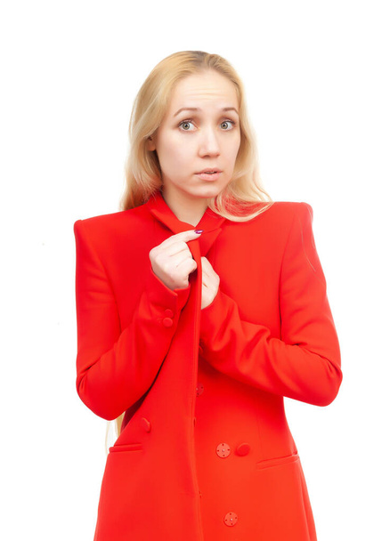 Ξανθιά κοπέλα με μια έκφραση έκπληξης στο πρόσωπό της με κόκκινα ρούχα σε λευκό φόντο. - Φωτογραφία, εικόνα