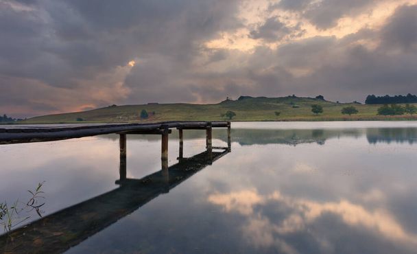 Landschap van een steiger op een dam met dramatische regenwolken - Foto, afbeelding