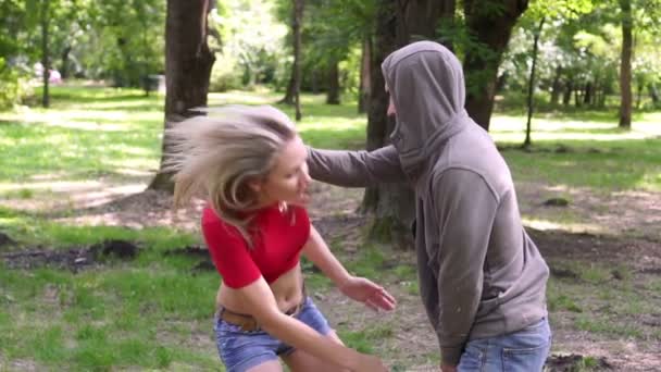 Een vrouw traint in een park voor zelfverdediging en hand-aan-hand gevechten. - Video