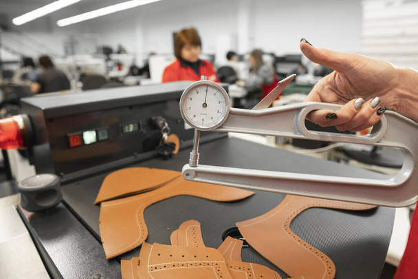 Woman hands use Leather thickness gauge on with a natural brown leather. Preparing of the raw materials for manufacture of bags, shoes, clothing and accessories. - Foto, immagini