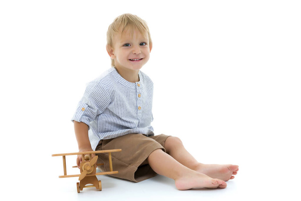 Little boy playing with wooden plane - Фото, изображение