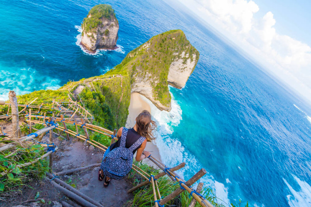 Νεαρή γυναίκα στέκεται και βλέποντας όμορφη θέα στο νησί Nusa Penida στο Μπαλί, Ινδονησία - Φωτογραφία, εικόνα