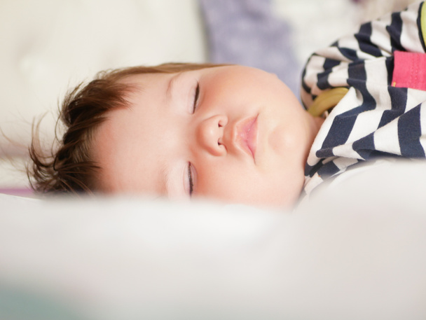 A baba a szülők ágyában alszik. a karok kinyújtják a baba nyugodt álmát. Közelkép. 0-1 éves gyermek. imádnivaló szép baba alszik nyugodtan az ágyban, van egy kellemes egészséges édes álom, gondoskodott. Hatás - Fotó, kép