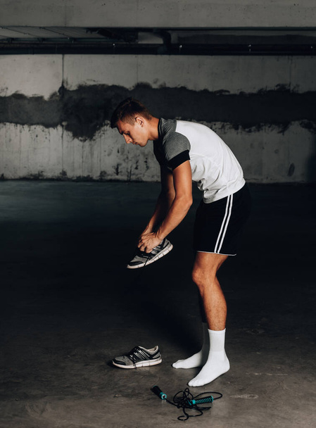 Sportieve man verkleedt schoenen voor training - Foto, afbeelding