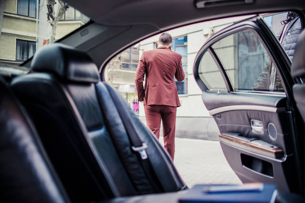 Jeune homme d'affaires est dehors et parle sur mobile près de la limousine
 - Photo, image