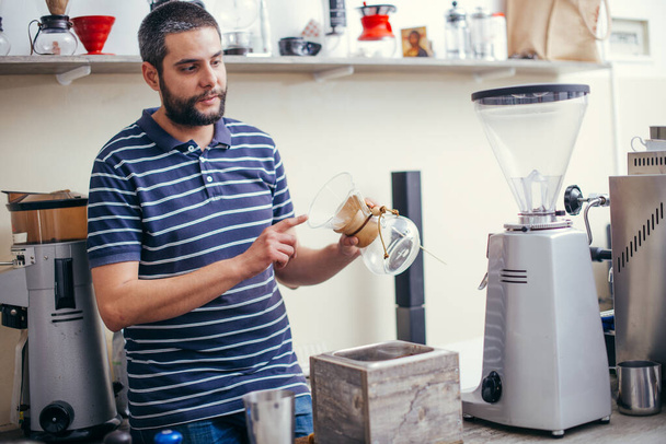 Hamdsome barista maakt koffie espresso in zijn koffieshop - Foto, afbeelding